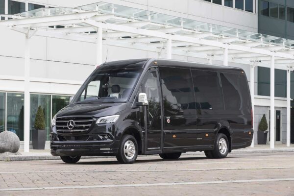 A black mercedes sprinter 16 seater party bus parked in front of an apartment complex